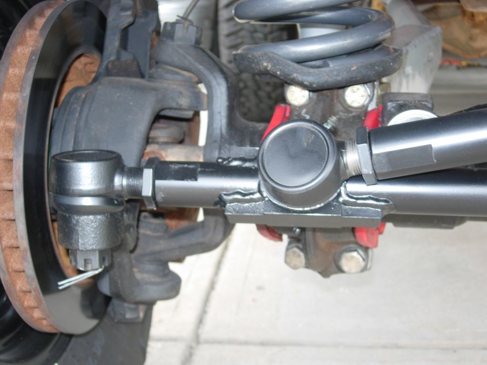 Close-up of heavy-duty tie rod end and drag link on a solid front axle knuckle