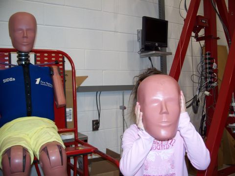 1971 Ford Ranchero - Two crash test dummies are in a laboratory setting, with one holding a mask over its face.