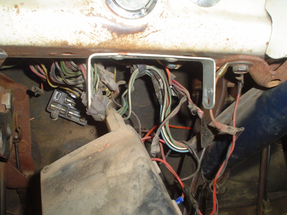 Close-up of a messy vehicle wiring harness with a fuse box and many colored wires