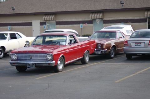 1967 Ford Ranchero - A red 1967 Ford Ranchero is parked next to other vehicles in a lot.