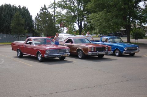 1967 Ford Ranchero - Three pickup trucks, including a 1967 Ford Ranchero, are parked in a lot on a sunny day.