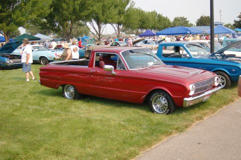 1967 Ford Ranchero - Red 1967 Ford Ranchero pickup truck displayed at a car show with other vehicles present.