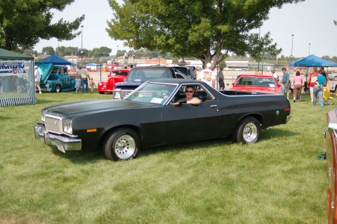 1967 Ford Ranchero - A black Ford Ranchero is displayed at a car show with other vehicles in the background.