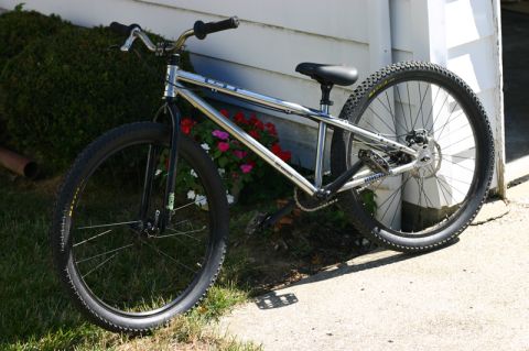 1997 Ford Probe - A chrome bicycle with knobby tires and disc brakes is parked next to a white wall.