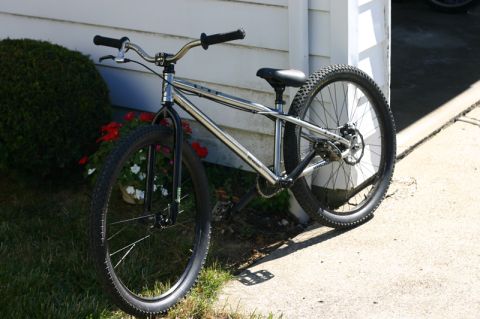 1997 Ford Probe - Chrome BMX bike with knobby tires parked next to a white wall and green bush.