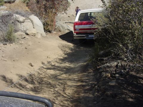 1994 Ford Bronco - Ford Bronco navigating a rough, dusty trail with brush and rocks.