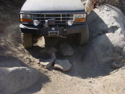 1994 Ford Bronco - A Ford Bronco is shown off-roading over rocks and dirt.