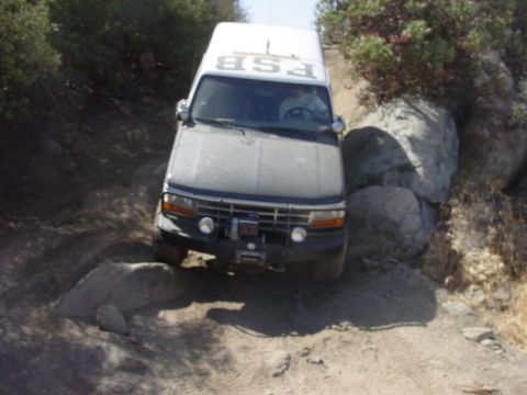 1994 Ford Bronco - A white van with 'FSB' visible on its roof navigates a challenging, rocky off-road path.