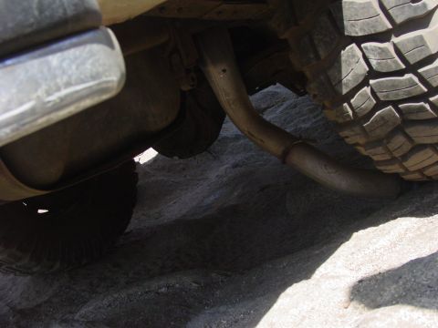 1994 Ford Bronco - Close-up of a vehicle's undercarriage, focusing on the exhaust system and tire.