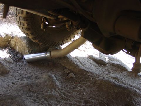 1994 Ford Bronco - The exhaust pipe of an off-road vehicle is visible, resting on rocky terrain.