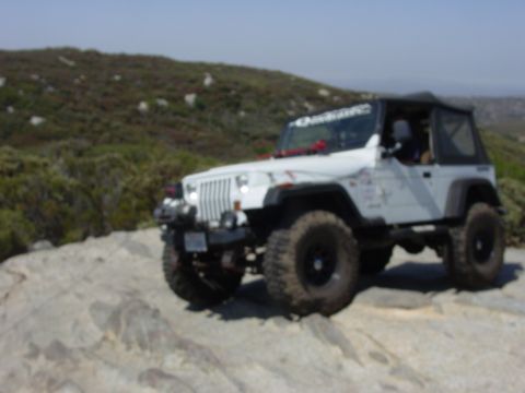 1994 Ford Bronco - A white Jeep Wrangler navigates a rocky trail, its off-road capabilities.