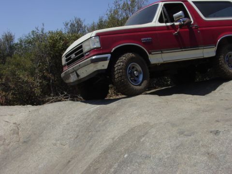 1994 Ford Bronco - This Ford Bronco is navigating a rocky terrain with its tires angled on the uneven surface.