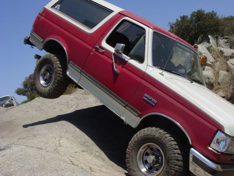 1994 Ford Bronco - A 1994 Ford Bronco navigates a rocky trail, with another vehicle visible in the background.