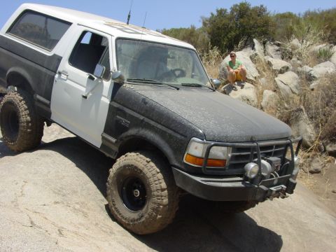 1994 Ford Bronco - Modified 1994 Ford Bronco tackling a challenging off-road course with large rocks.