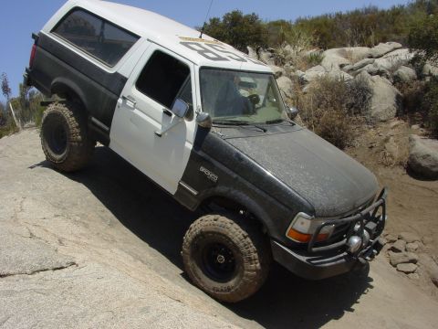 1994 Ford Bronco - This modified Ford Bronco is navigating a rocky trail under a clear blue sky.
