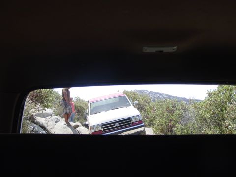 1994 Ford Bronco - A white and red SUV navigates a rocky trail, with a visible grille indicating a 1992 model year.