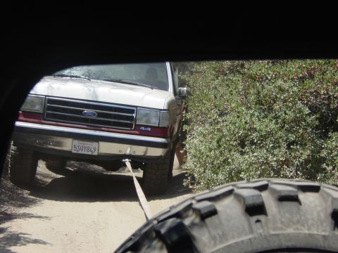 1994 Ford Bronco - A tow strap connects this Ford F-Series truck to another vehicle off-camera as it navigates a dirt path.