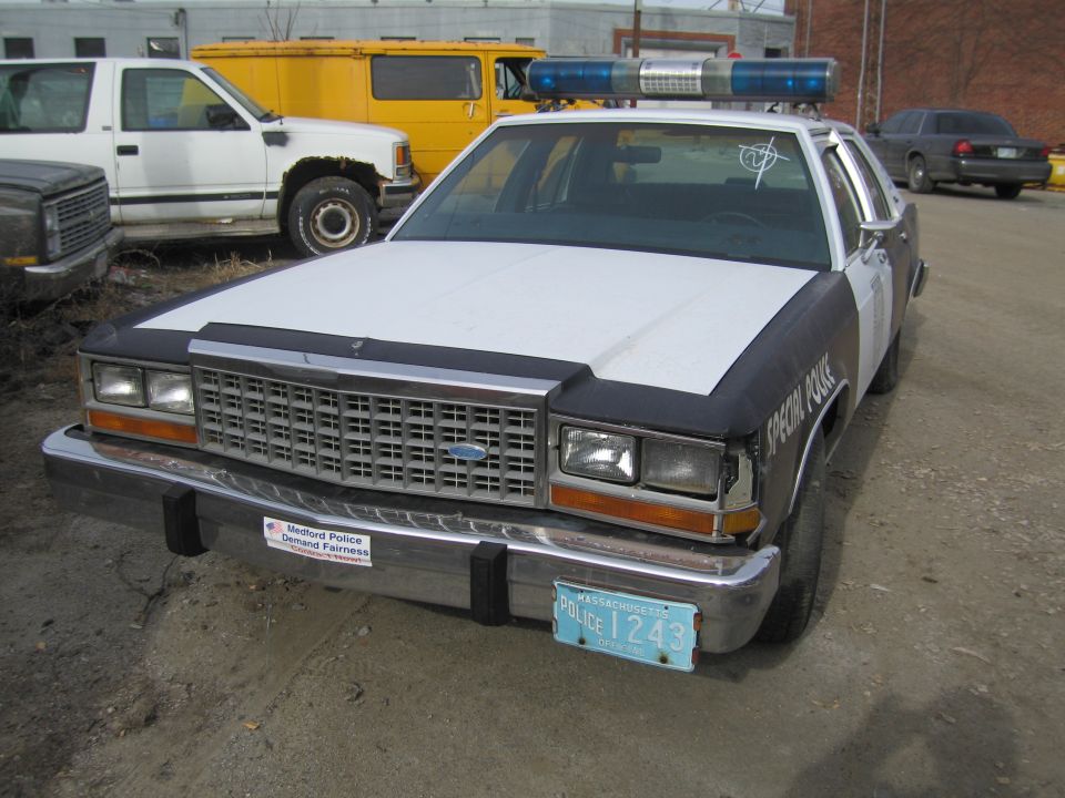 Front view of a 1991 Ford Crown Victoria police car with a light bar. Medford Police sticker on bumper