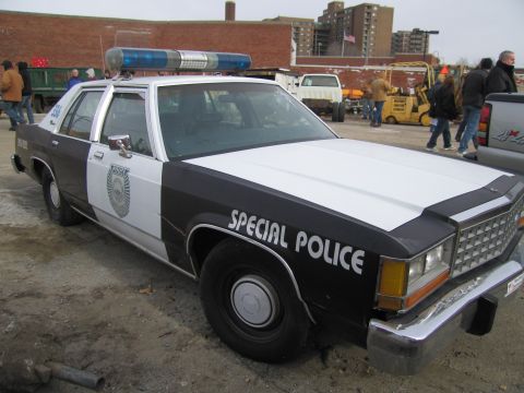 1991 Ford LTD Crown Victoria - A two-tone police car with "SPECIAL POLICE" text is parked outdoors with other vehicles and people in the background.