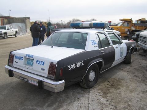 1991 Ford LTD Crown Victoria - Three-quarter rear view of a black-and-white Ford LTD Crown Victoria police sedan lettered "MEDFORD SPECIAL POLICE" on the trunk with unit…