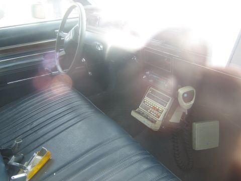1991 Ford LTD Crown Victoria - Interior view of a car's dashboard and seats, equipped with a police radio and microphone.