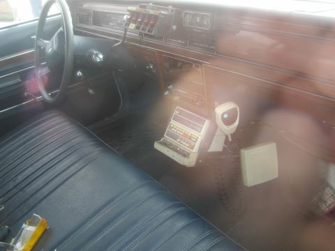1991 Ford LTD Crown Victoria - The interior of a car features a police radio and microphone, along with wood-grain trim on the dashboard.