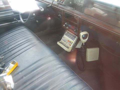 1991 Ford LTD Crown Victoria - The interior of a car features a vintage police radio setup with a microphone and control panel mounted on the dashboard.