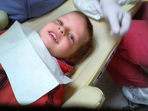 1989 Ford Bronco - A young child sits in a dentist's chair, wearing a bib, as a dental professional prepares for an examination.