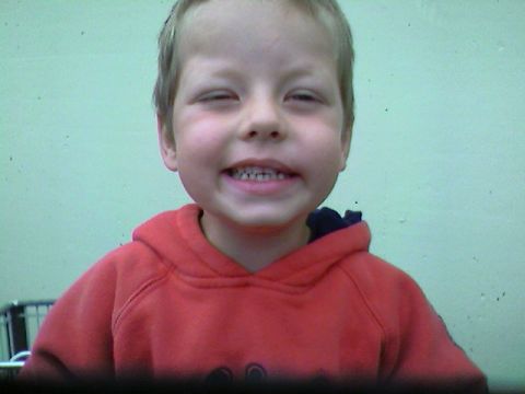 1989 Ford Bronco - A young child smiles broadly, wearing a red hooded sweatshirt against a light green wall.
