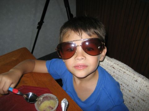 1986 Ford Bronco - A young boy with aviator sunglasses on sits at a table, holding a spoon.