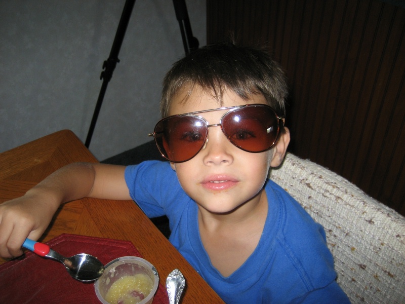 Child in blue shirt and aviator sunglasses at a table