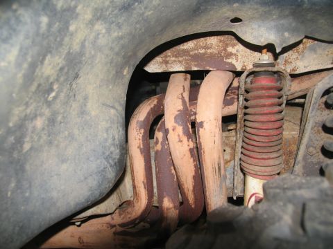 1978 Ford Bronco - The underside of a vehicle shows rusty exhaust pipes and a red shock absorber, indicating wear and tear.