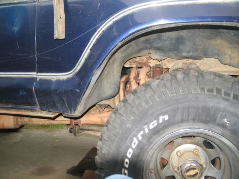 1978 Ford Bronco - The rear wheel well of a blue vehicle is shown, with visible suspension and exhaust system parts.