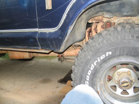 1978 Ford Bronco - Close-up view of the side of a blue vehicle, showing the tire, exhaust, and suspension components.