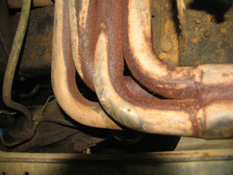 1978 Ford Bronco - Close-up view of rusty exhaust manifold pipes, likely from an older vehicle.