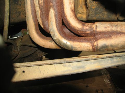 1978 Ford Bronco - The exhaust manifold shows significant rust and wear, indicating age and exposure.