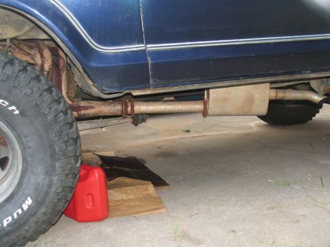 1978 Ford Bronco - A close-up view of a vehicle's undercarriage shows a rusty exhaust system and a tire.