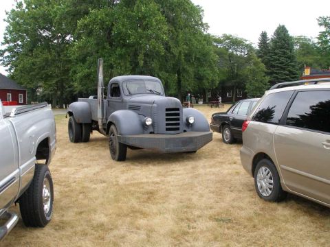 1997 Ford Taurus - A vintage gray truck with a tall exhaust pipe is parked on dry grass, surrounded by other vehicles.