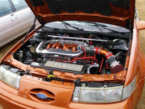 1997 Ford Taurus - Open engine bay of a custom orange Ford SHO showing the Yamaha-built V6 with body-color-painted intake runners, polished intake plenum and…