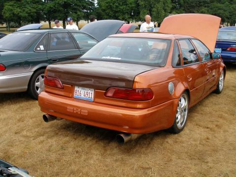 1997 Ford Taurus - A custom metallic orange Ford Taurus sedan shown from the rear three-quarter angle with its trunk/hood open, featuring a brown-tinted carbo…
