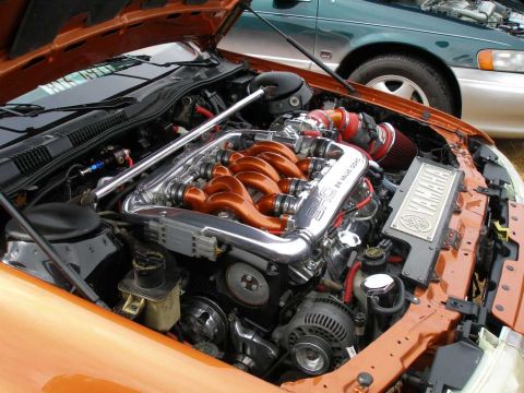 1997 Ford Taurus - Engine bay of an orange vehicle showing a highly polished chrome and orange Yamaha SHO 24-valve DOHC V6 engine with a strut tower brace, re…