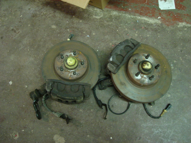 Two front brake rotor and caliper assemblies on a concrete floor