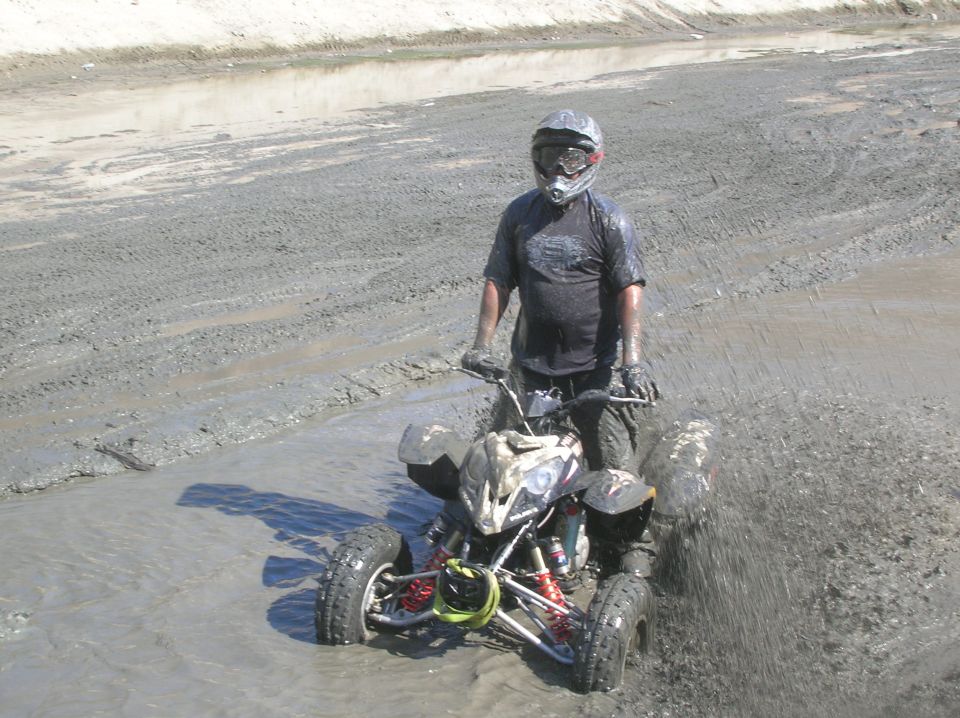 All-terrain vehicle with a rider in mud, front view