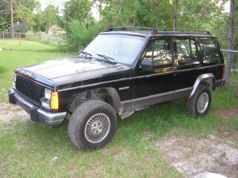 1974 Ford F-100 - A black Jeep Cherokee is parked outdoors on a grassy area with trees in the background.