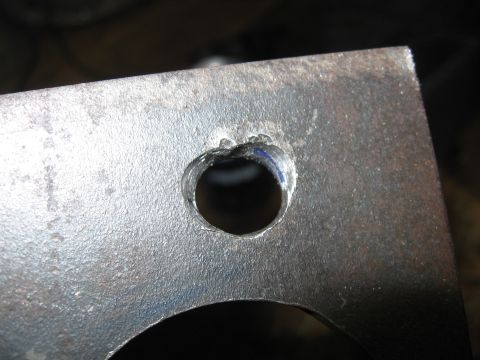 1974 Ford F-100 - A metal bracket with a hole is shown in close-up, with visible tool marks around the opening.