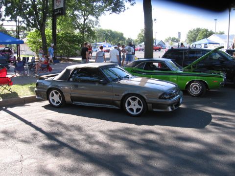 1989 Ford Mustang - A gray 1989 Ford Mustang convertible is parked at an outdoor car show with other vehicles.