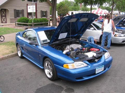 1989 Ford Mustang - A blue Ford Mustang is displayed with its hood up, revealing the engine compartment.