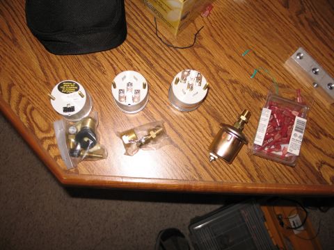 1995 Ford Bronco - Various gauges and electrical connectors are laid out on a wooden surface, suggesting parts for a vehicle's electrical system.