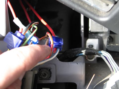 1995 Ford Bronco - Close-up of a hand connecting wires in a vehicle's wiring harness.