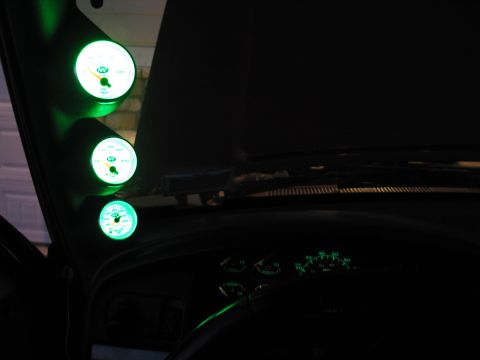 1995 Ford Bronco - Interior view of a vehicle's dashboard and A-pillar, showing multiple glowing green gauges.